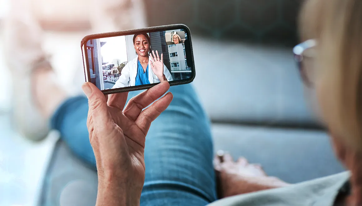 Woman reclining on the couch speaking virtually with a physician on her phone.